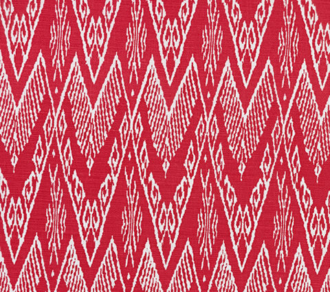 A close-up of a fabric with a geometric ikat print featuring zig zag motifs in a custom dark red on white color scheme.