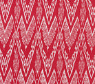 A close-up of a fabric with a geometric ikat print featuring zig zag motifs in a custom dark red on white color scheme.
